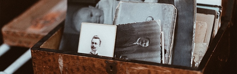 A wooden box containing black and white old photos.