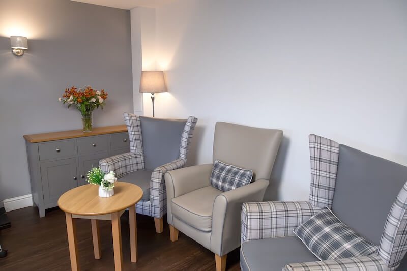 Three beige and checkered armchairs surrounding a small table.